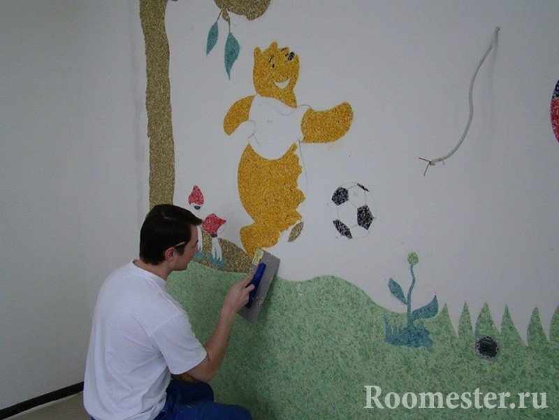 Мужчина рисует Вини-Пуха на стене в детской