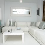 Белый угловой диван в интерьере гостиной