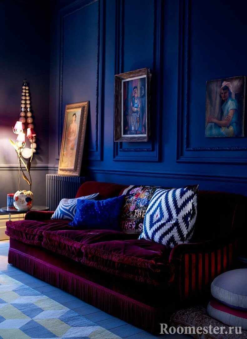 Бордовый диван на фоне темно-синих стен