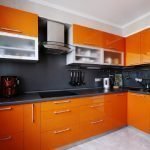 Однотонный черный фартук на оранжевой кухне
