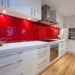 Белая мебель и красный фартук в интерьере кухни